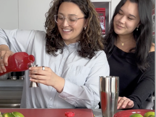 Two young women pour tequila into jigger while making a cocktail